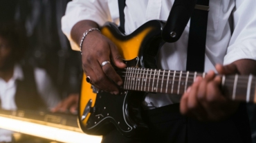 Gros plan sur un les main d'un guitariste qui joue de la basse