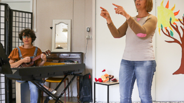 Photos d'une conteuse en pleine action, les mains indiquant une direction devant elle, accompagnée d'une musicienne jouant du yukulele