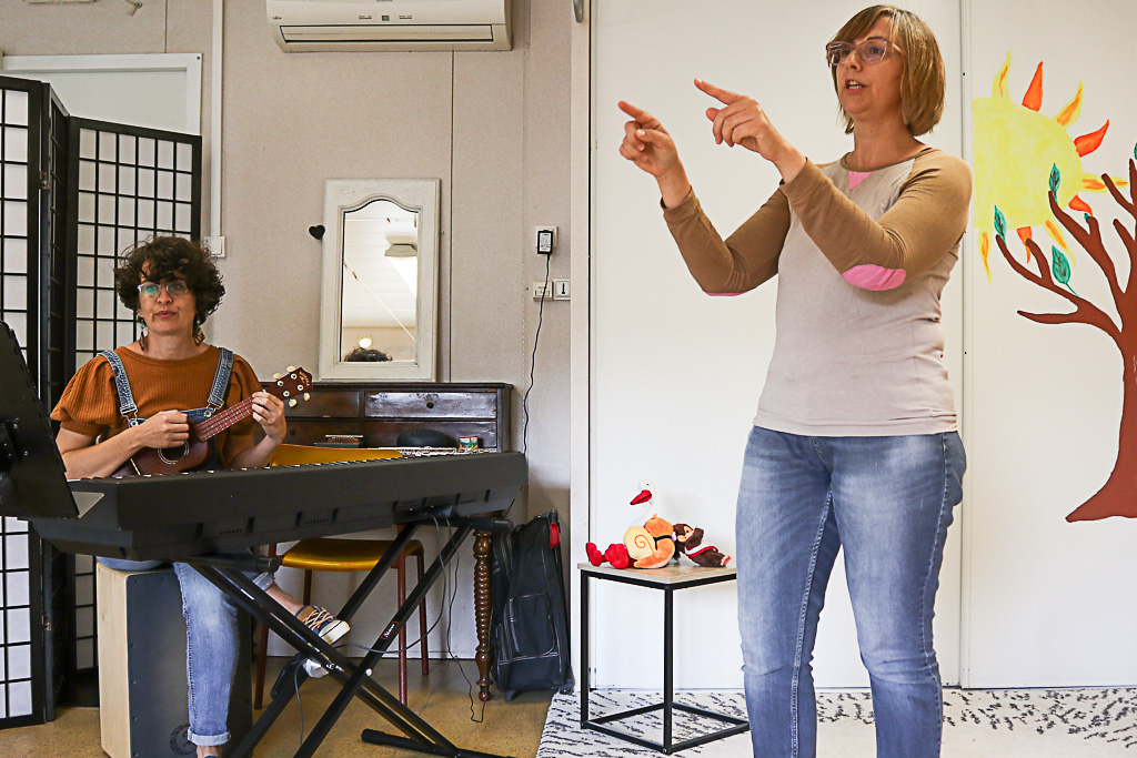 Photos d'une conteuse en pleine action, les mains indiquant une direction devant elle, accompagnée d'une musicienne jouant du yukulele