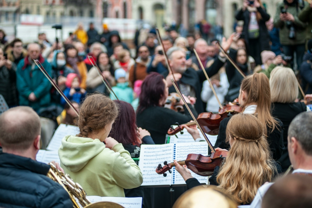 Orchestre de violons en train de jouer devant un public avec un chef d'orchestre
