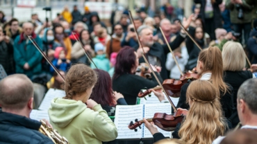 Orchestre de violons en train de jouer devant un public avec un chef d'orchestre
